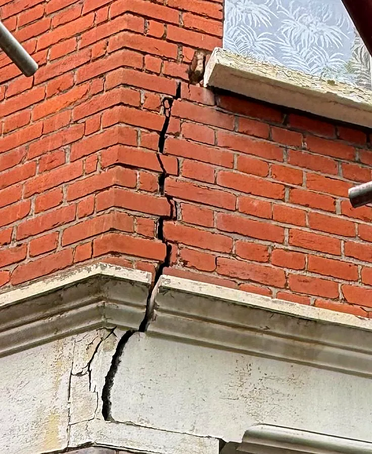 Stepped crack running through a brick corner and cornice, ready for Helifix crack stitching, London